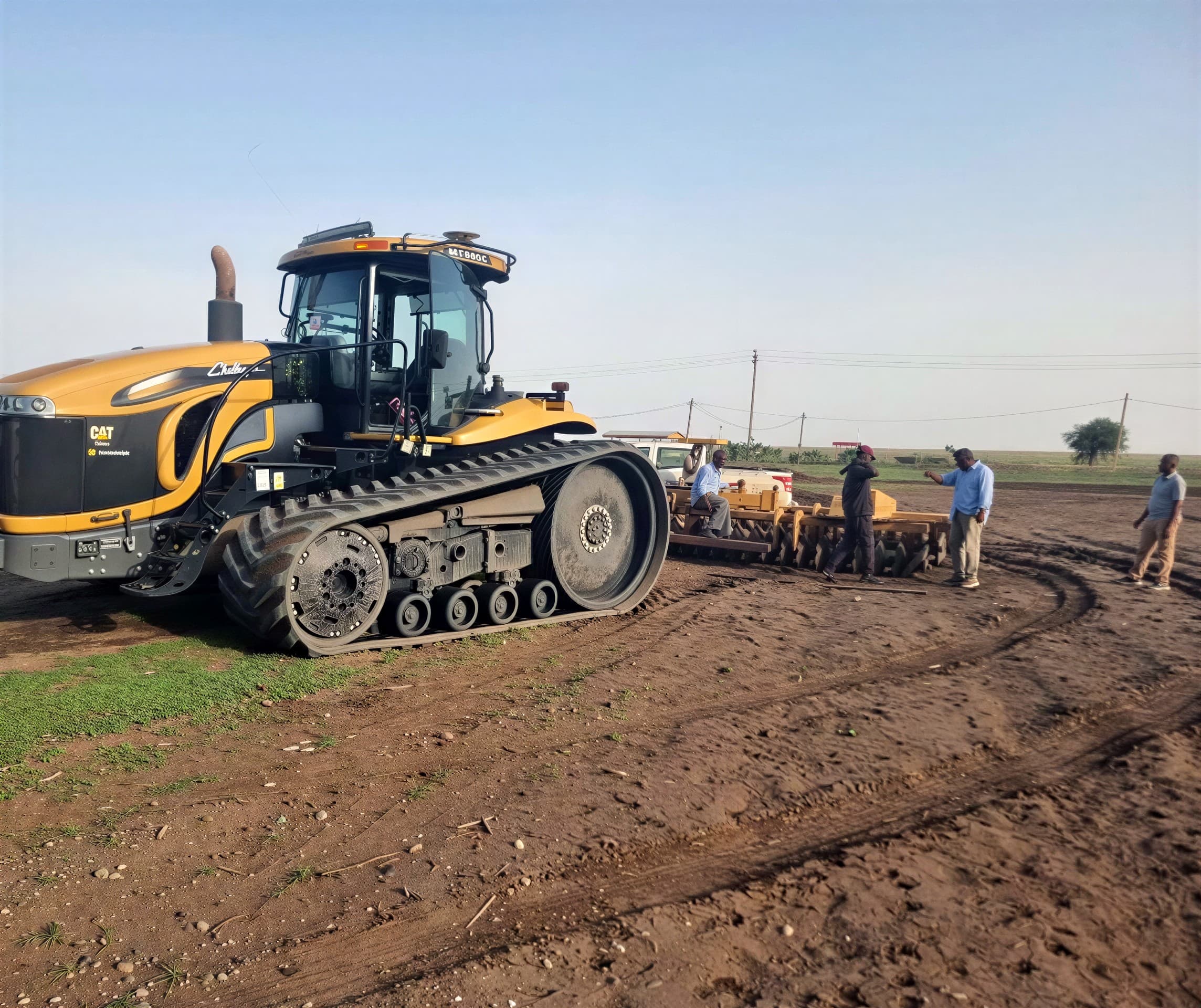 Field crew beside a Challenger tracked tractor and disc harrow before work.